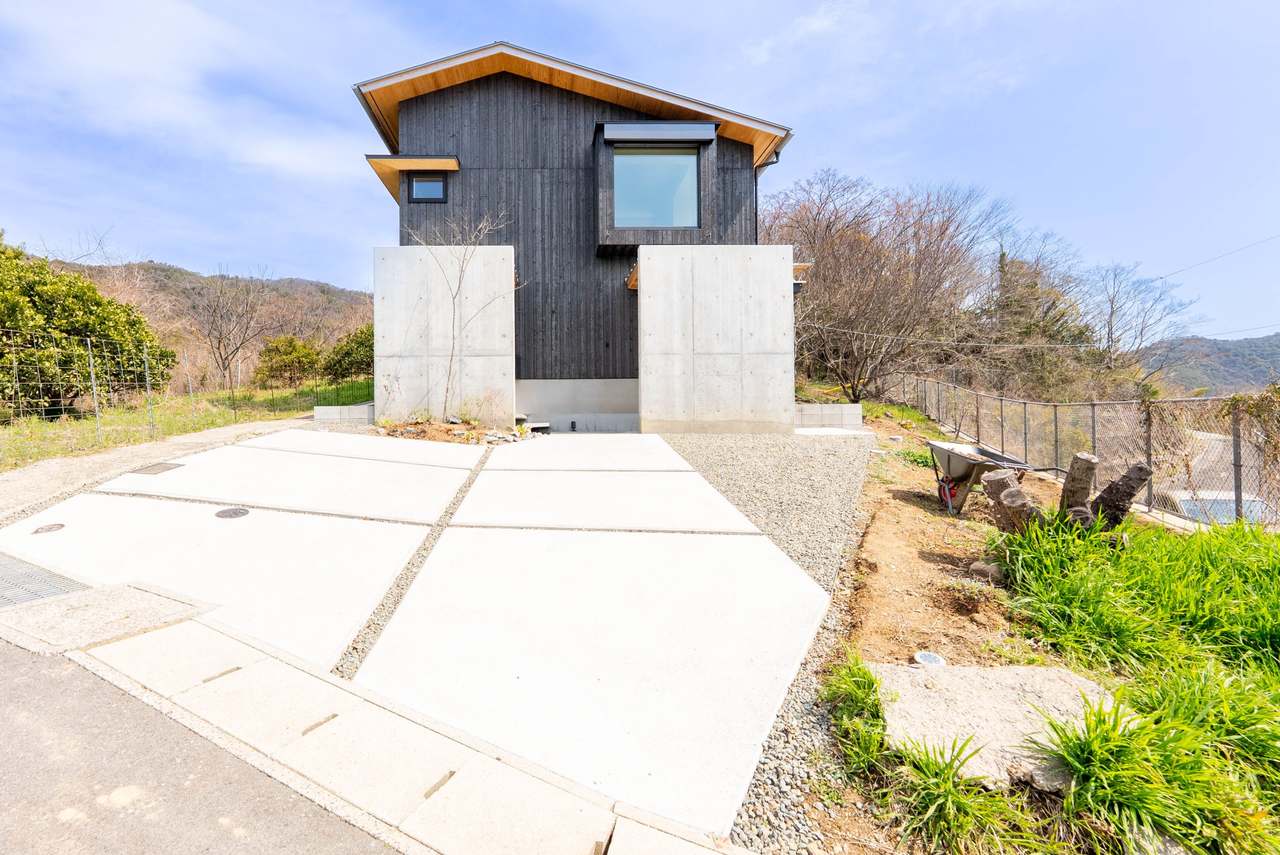 沼隈の家の外観。板張りの切妻屋根が草地に建つ