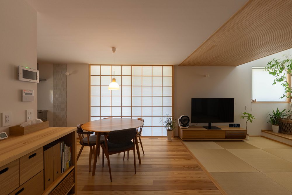 無垢の床板と漆喰の壁に囲まれた居間。窓から光が差し込み、木の建具が見える