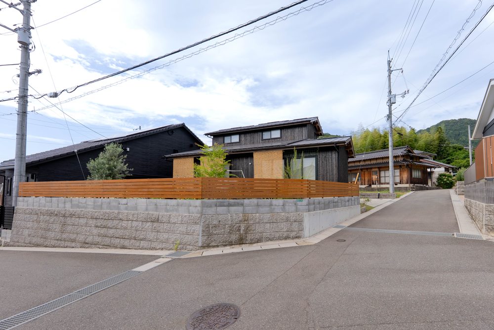 前面道路から見た住宅の外観。左右に隣家が並び、街並みの中に建っている
